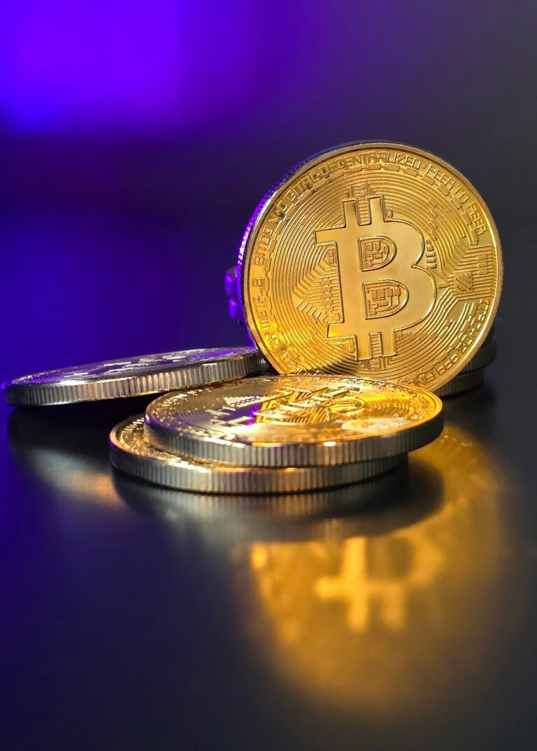 Златни биткойн монети на син и лилав фон
